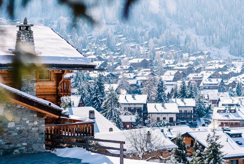 A wooden chalet is just in shot in the foreground, the snowy village extending in the background of the photo