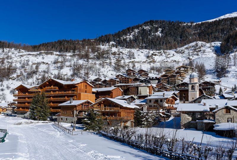Wooden buildings sit in a snowy setting