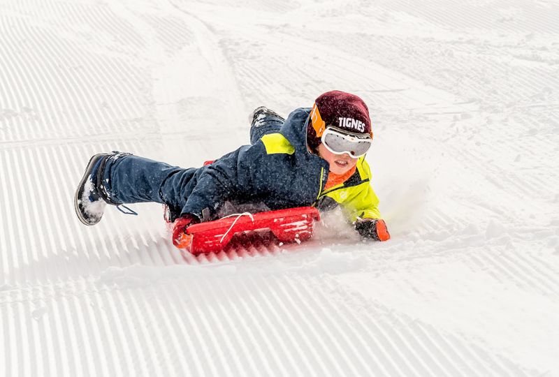 a child sledges down a piste on his belly