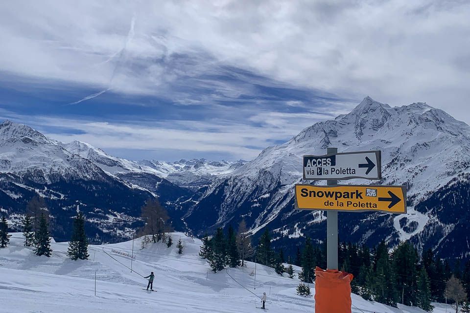 Ski hill and sign and mountain range in the background