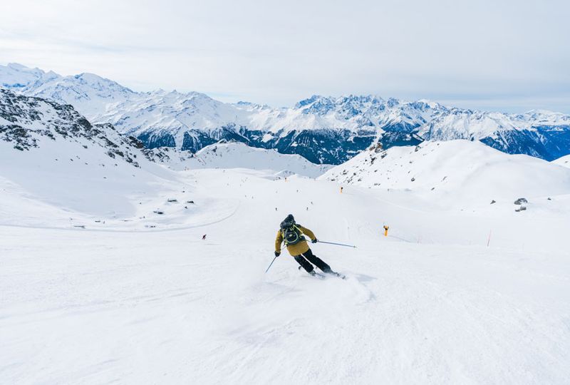 A skier turns down an empty, wide piste