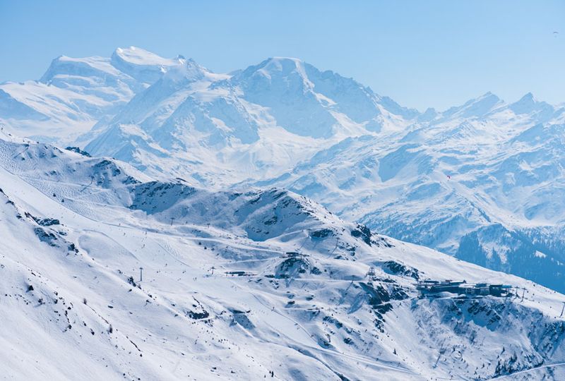 A huge white mountainscape shows huge, tall, snowy mountains, resort lifts and plenty of freeriding terrain in this powerful shot