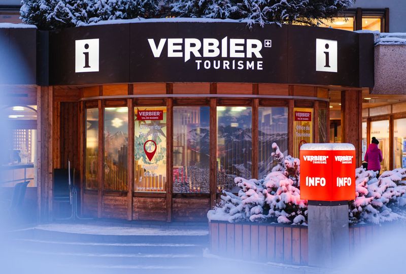 The modern, wood front of Verbier tourism office is caught at low light