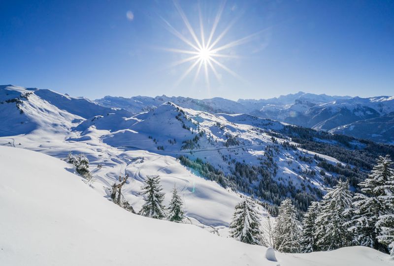 Shining sun, blue sky and a white mountainscape