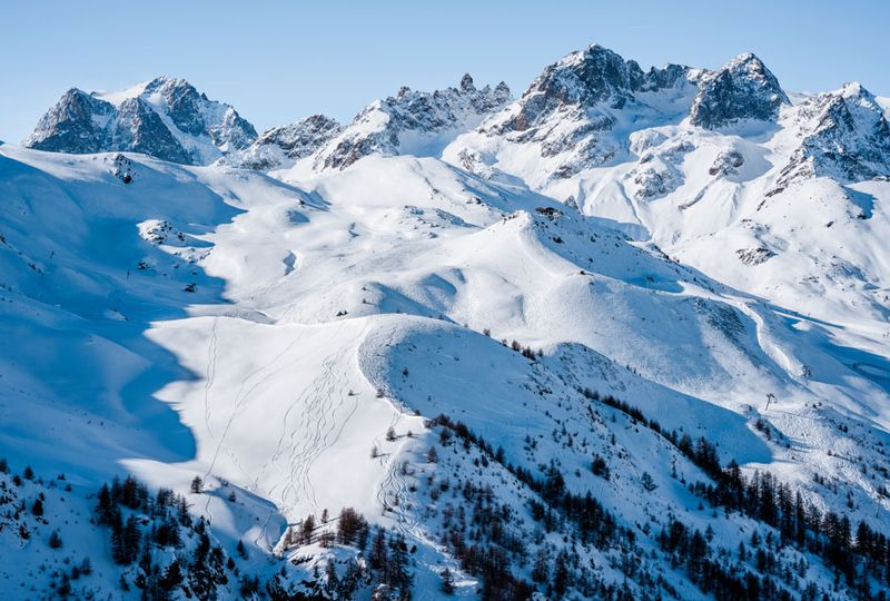 A drone shot of a huge, beautiful, snowy ski area, from jagged peaks to smooth groomed slopes