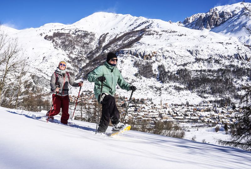 Two people snowshoeing through fresh powder, above the village