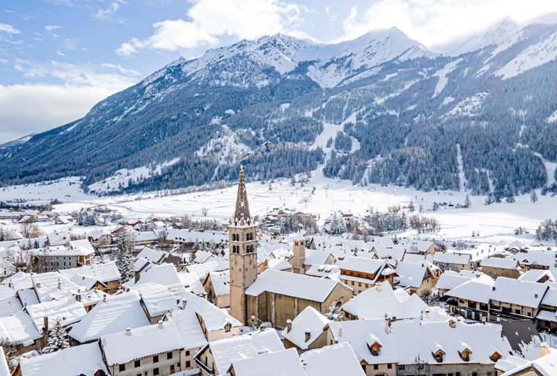 A snowy church steeply and village under snow