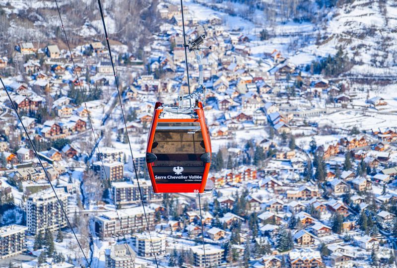 A red lift cabin high above a snowy alpine village