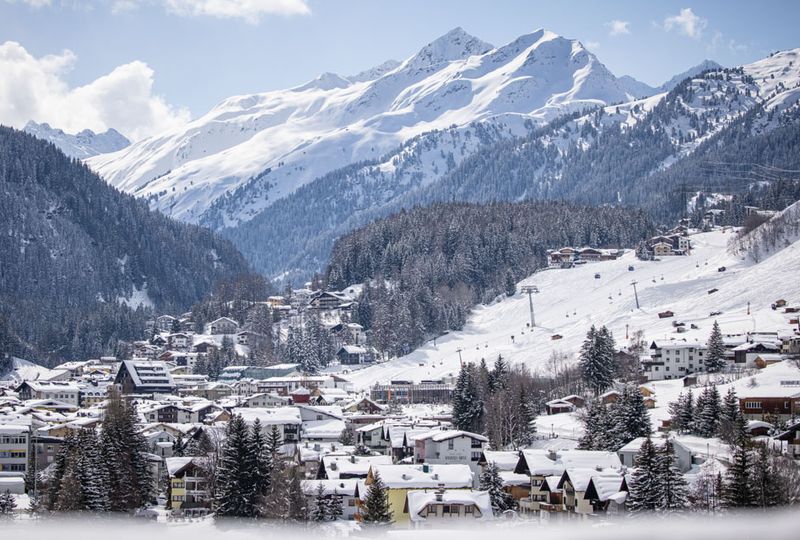 Snowy village is pictured, with the lift line, snow-dusted trees and white mountains surrounding