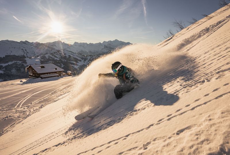 It's low light and a skier sprays snow on a deep turn off piste. The light makes it seem like dusk