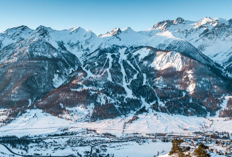 A distant look at the slopes of Monetiers, runs cut into the alpine, snow on the ground everywhere