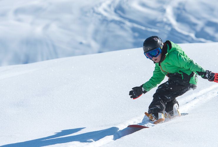 Child snowboards in powder in Les Menuires