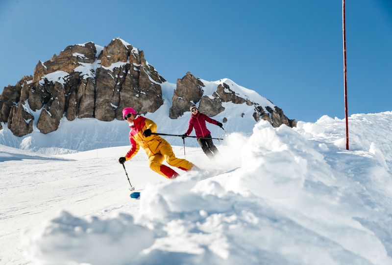 two skiers turn on piste